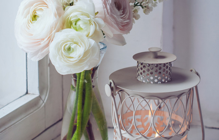 Home festive decorations elegant bouquet of flowers buttercups and white lilac and candle lantern on white vintage windowsill